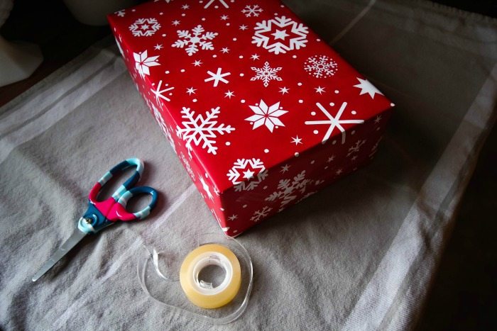 Roll Of Wrapping Paper Scissors Gift Bow And Box On Wooden Table