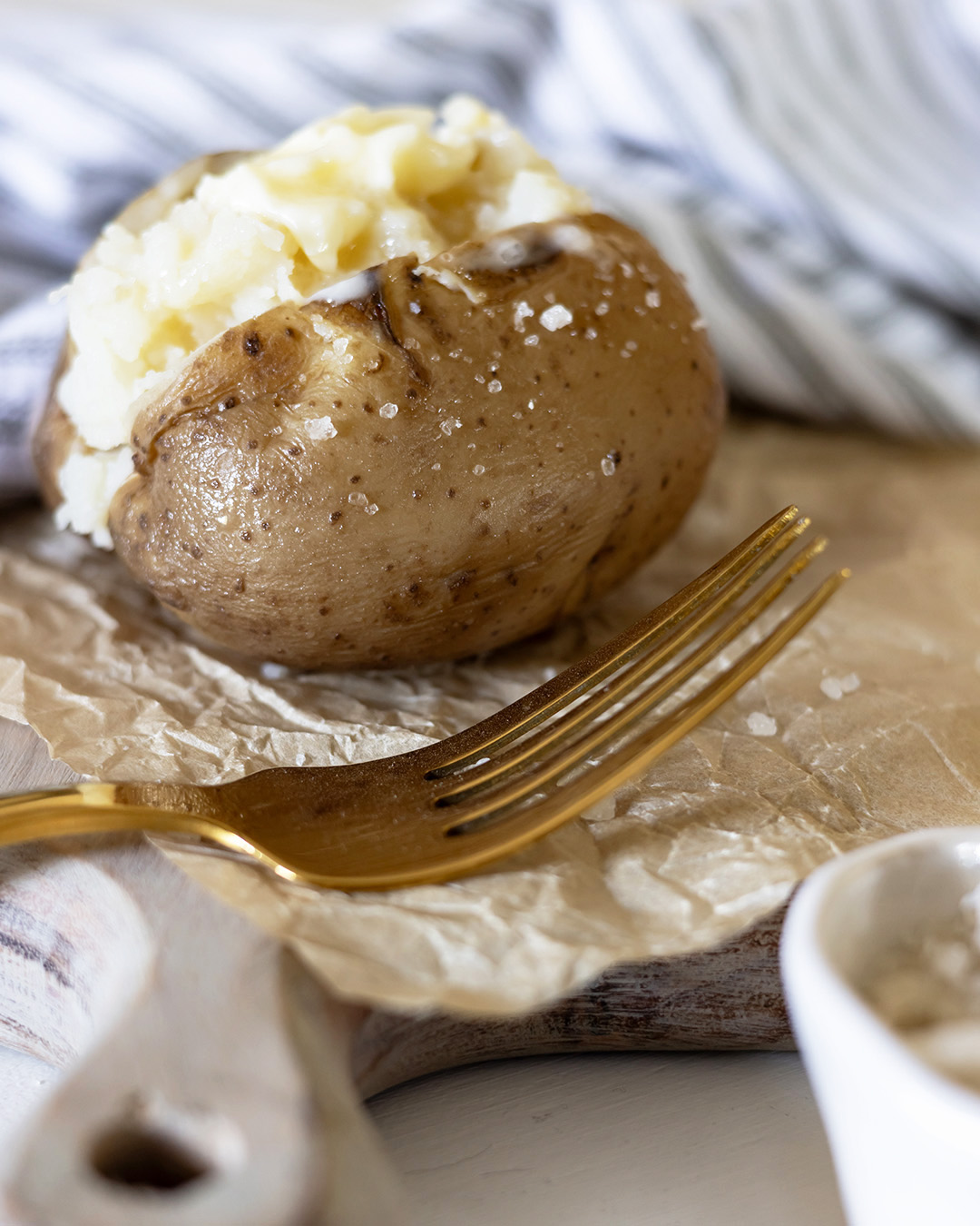 Crock pot baked potato with gold fork and striped towel