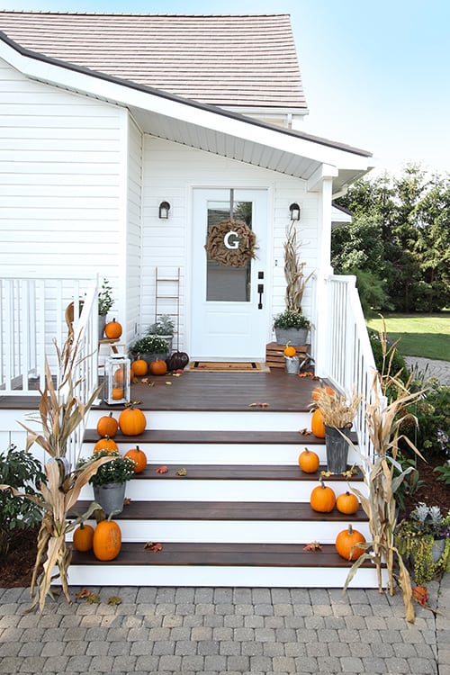 A fall porch decorated with lots of bright orange pumpkins.