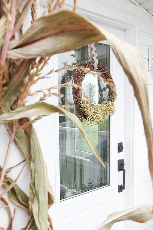 A grapevine and hydrangea wreath hanging on a front door.