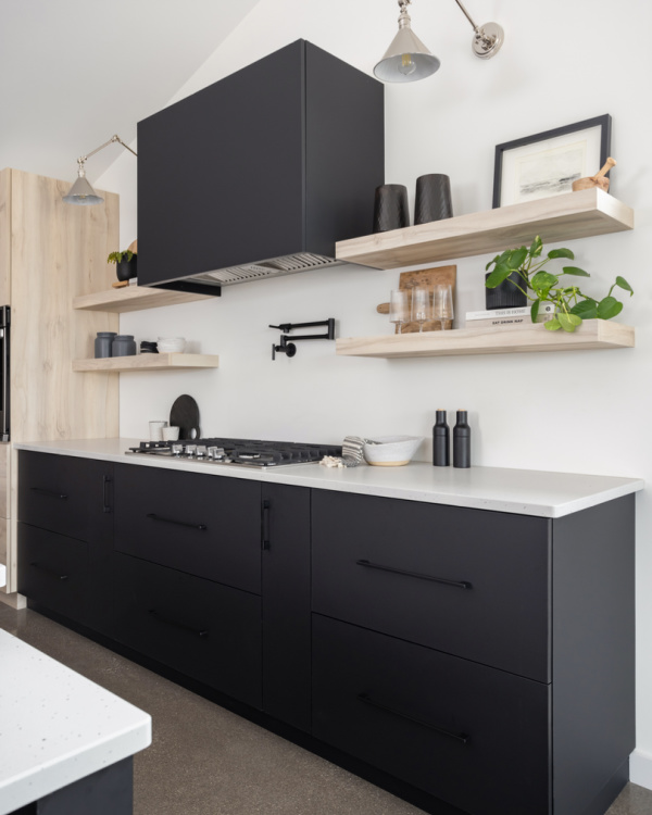 Modern flat front cabinetry with black range hood and blonde wood accents.