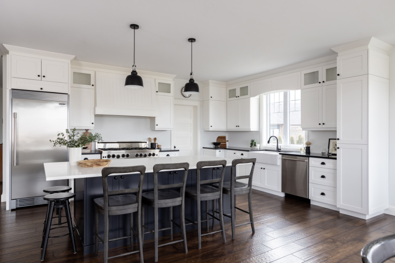 Traditional white kitchen with a black island and black pendant lights