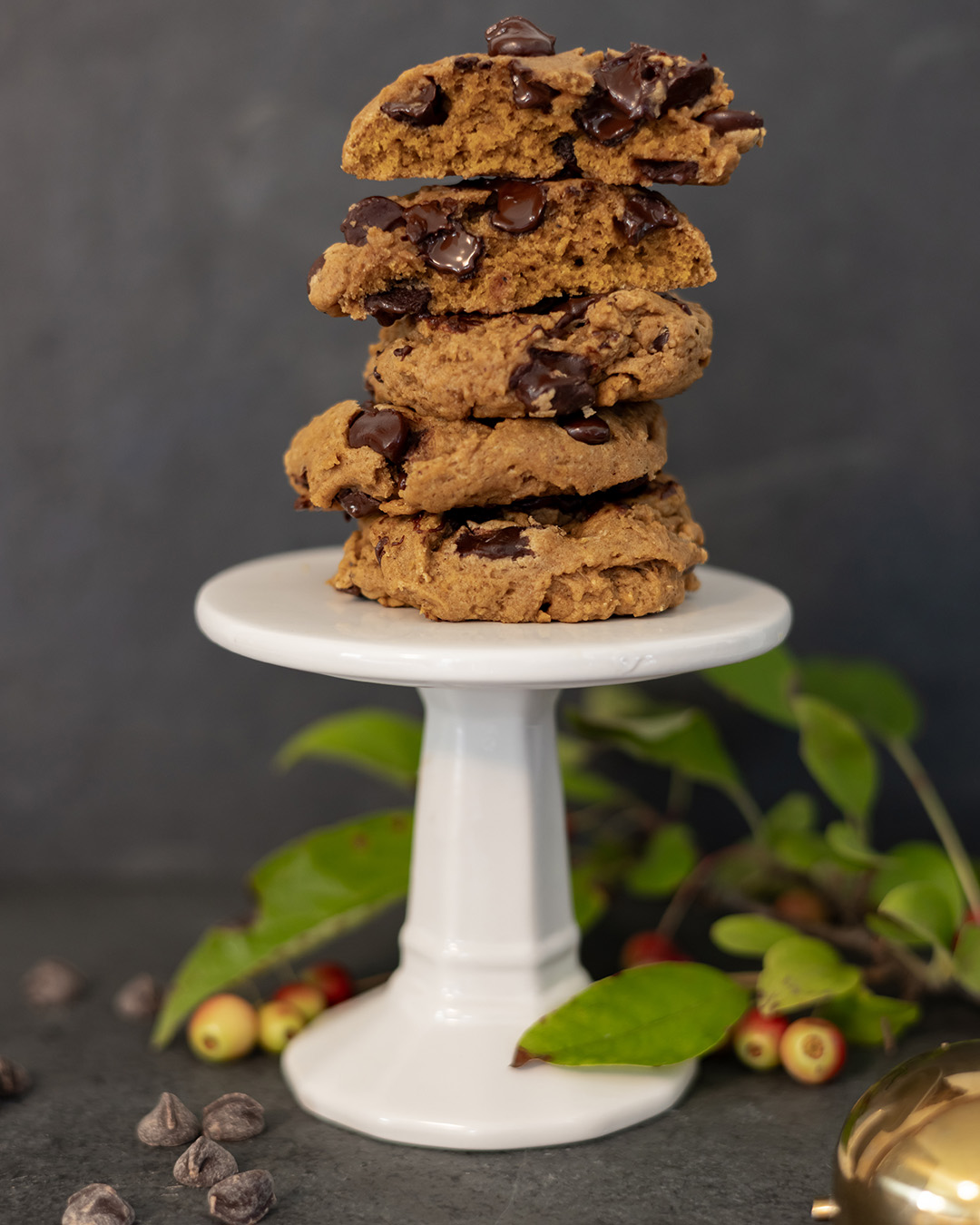 A stack of cookies with one split in half to show texture and melted chocolate chips.