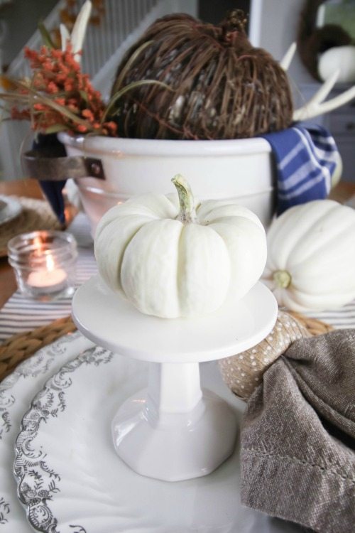 Thanksgiving centrepiece variation with a rattan pumpkin in a ceramic crock.