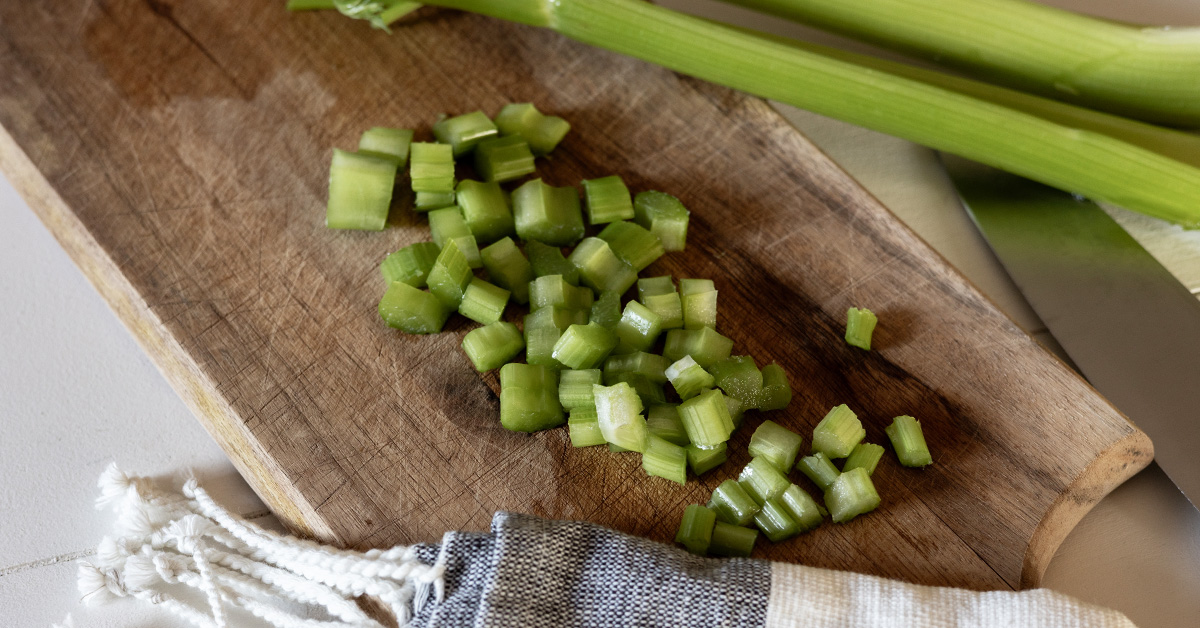 Diced celery on a wood cutting board.