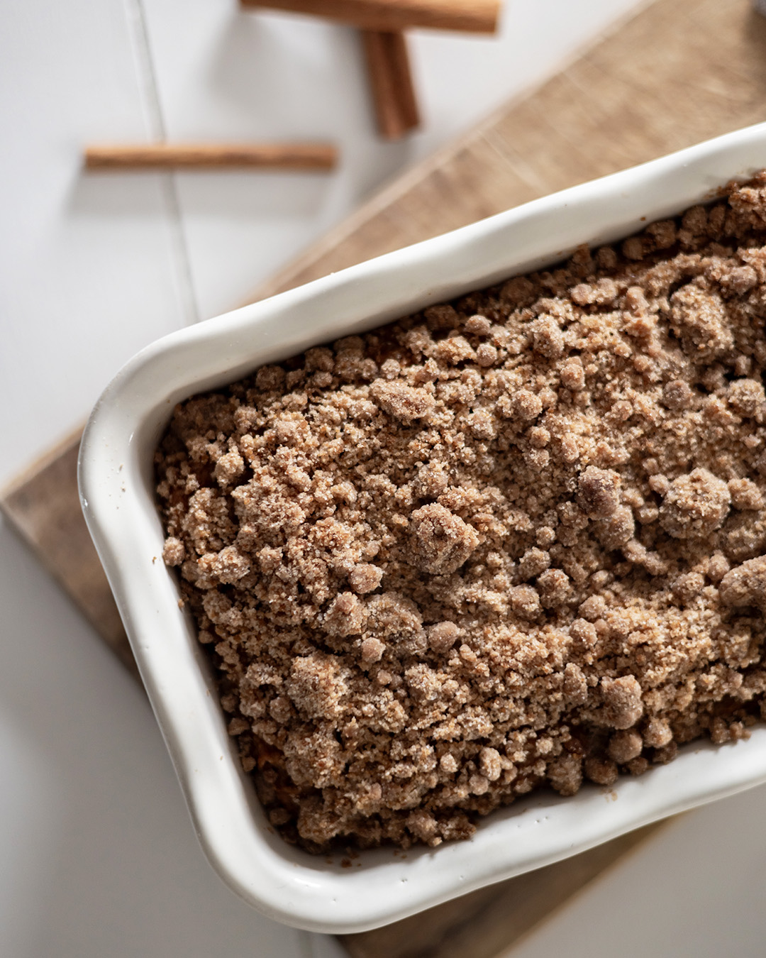Detail photo of apple bread with streusel topping in a white ceramic baking dish.
