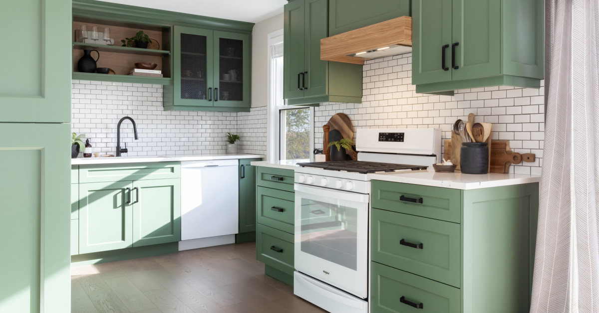 A bright and sunny kitchen with green cabinetry and white appliances.