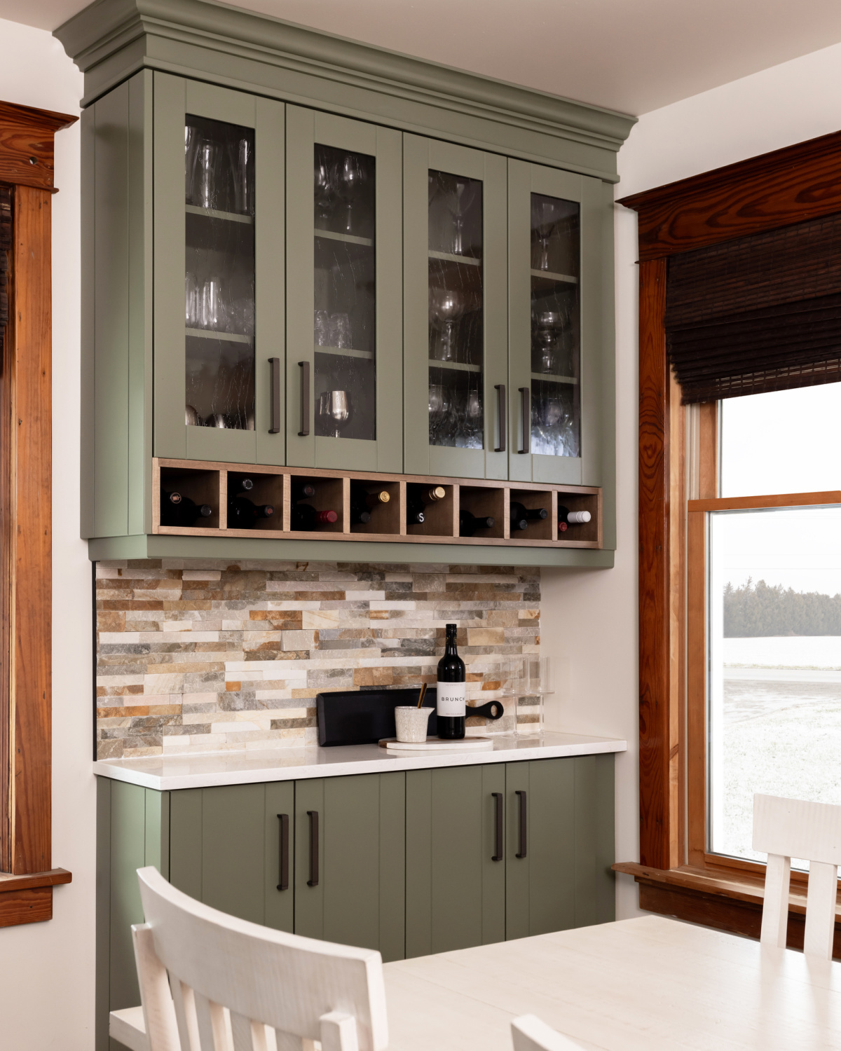 Built-in bar area with glass and green cabinets.