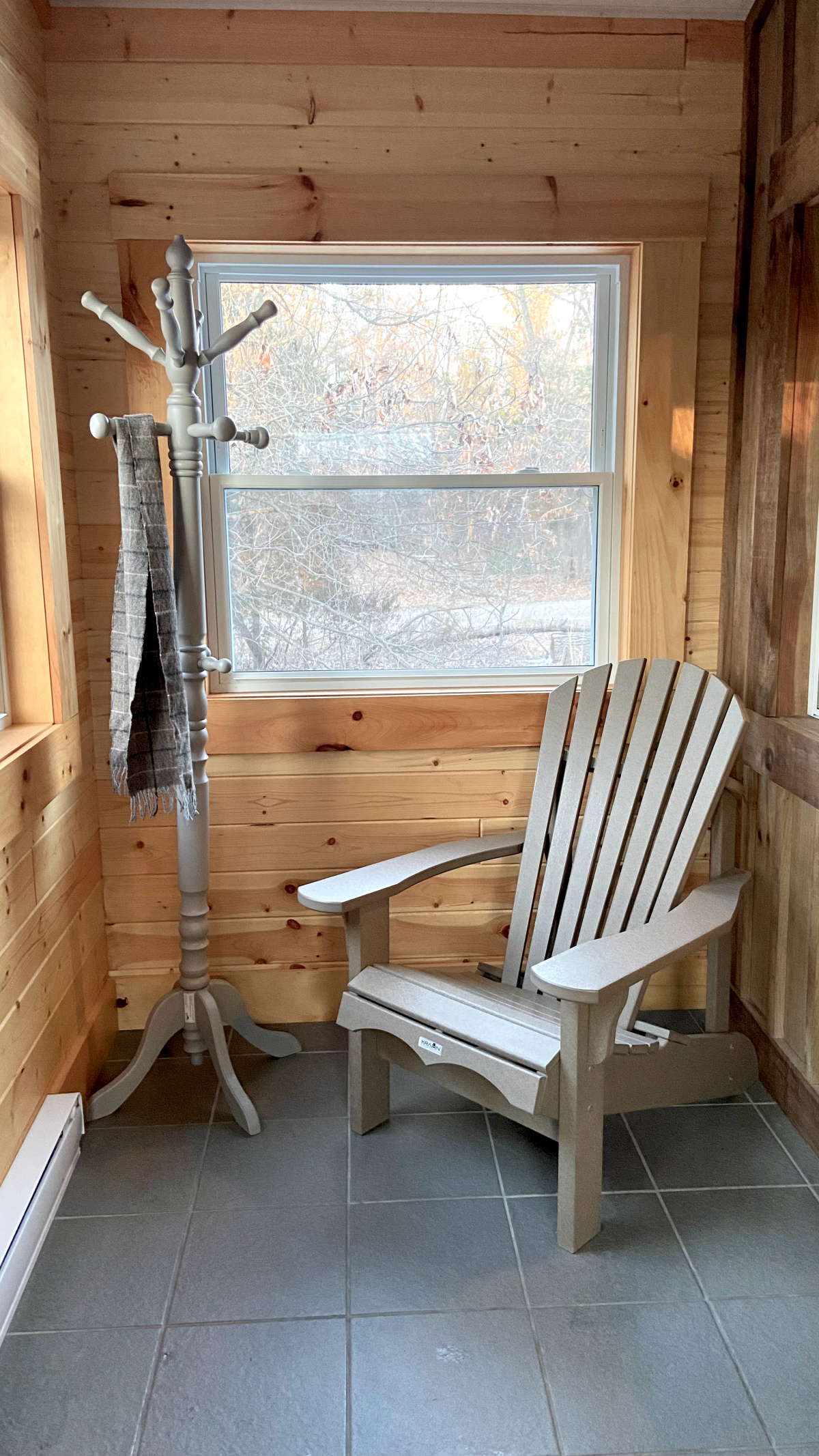 A coat rack and Adirondack chair in the cute cabin mudroom.