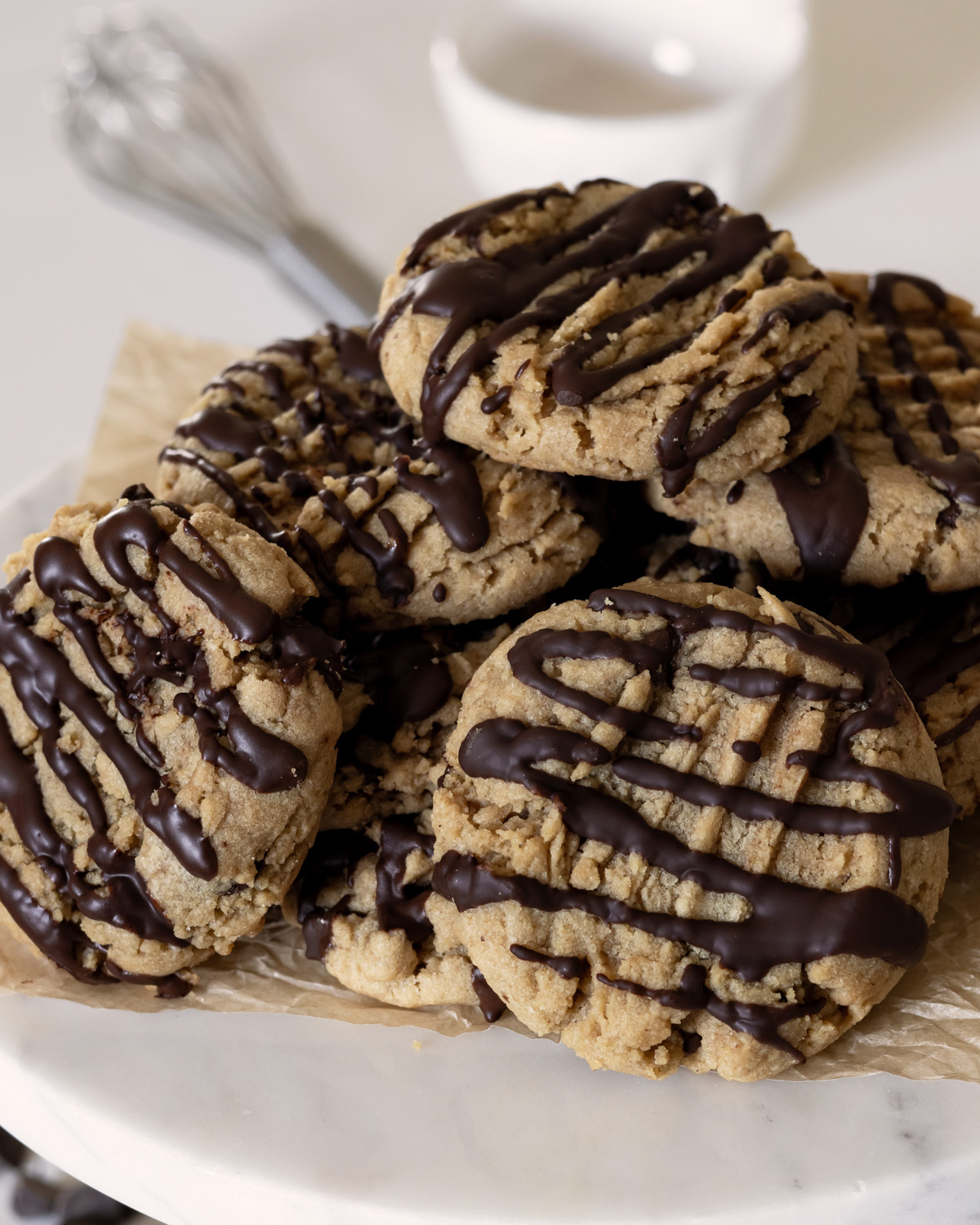 cookies with a chocolate drizzle stacked on a serving tray.