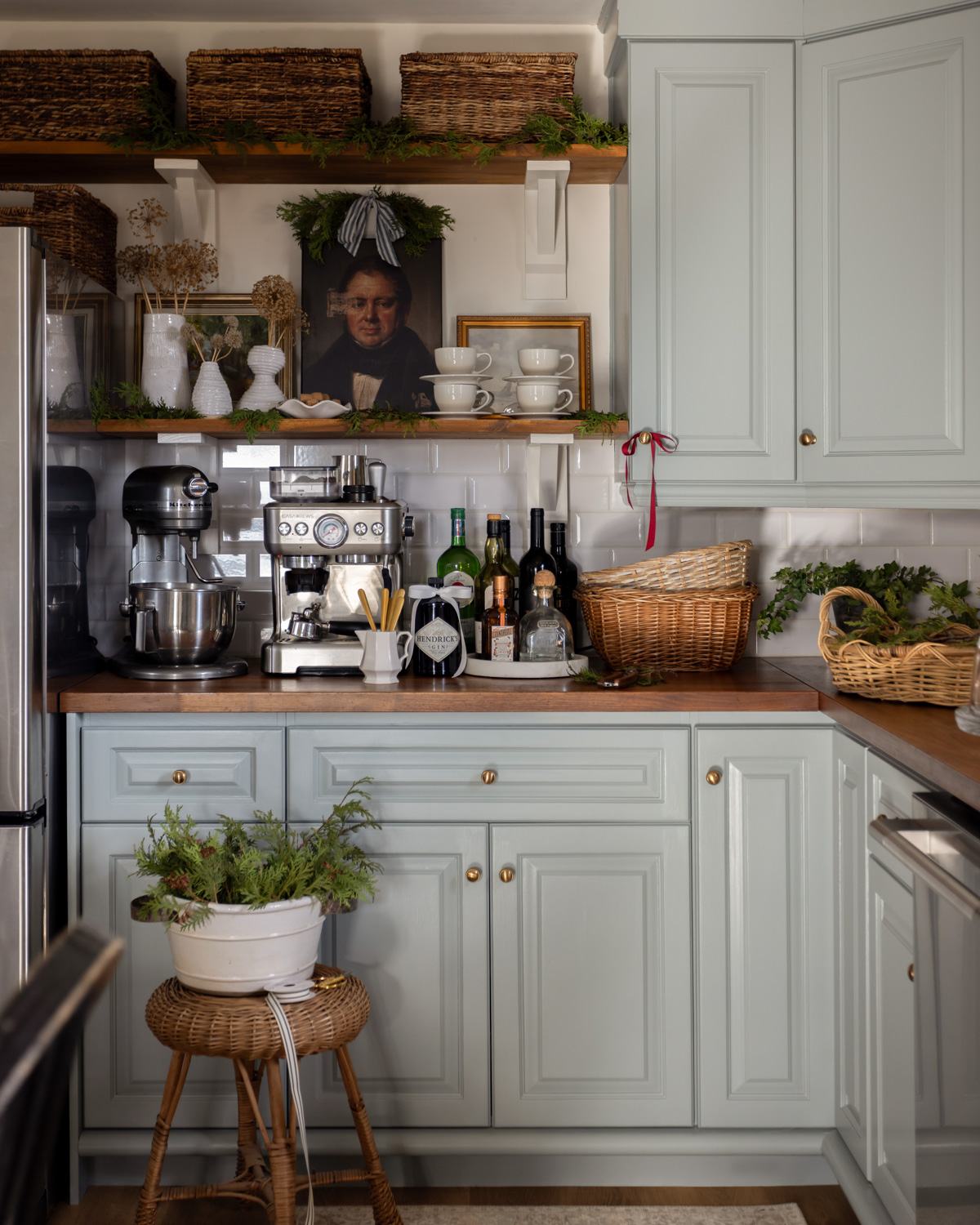 Christmas coffee bar with blue cabinets, espresso machine, and fresh greenery.
