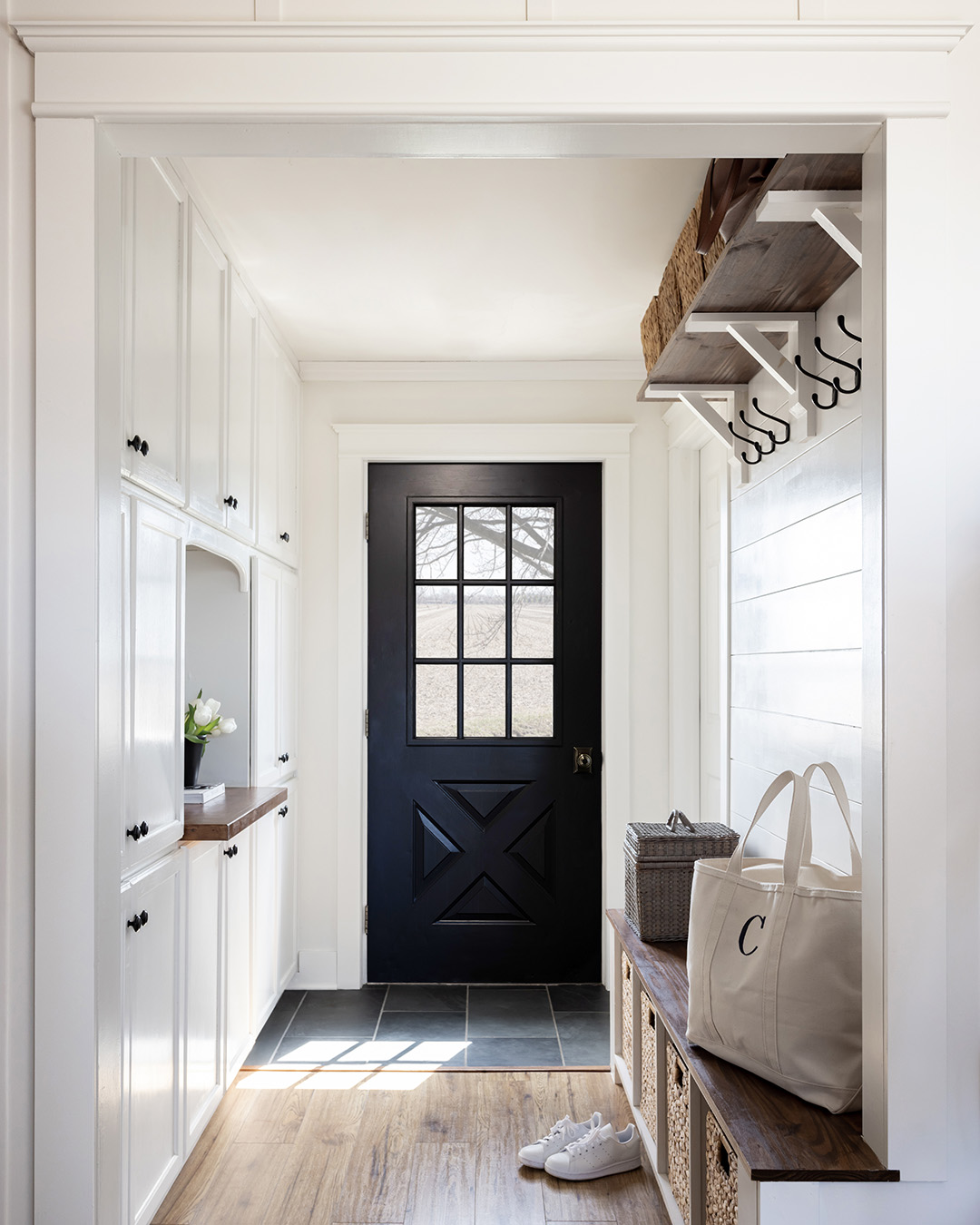 A storage-filled mudroom with cubbies, hooks, shelves, and a wall of cabinetry.