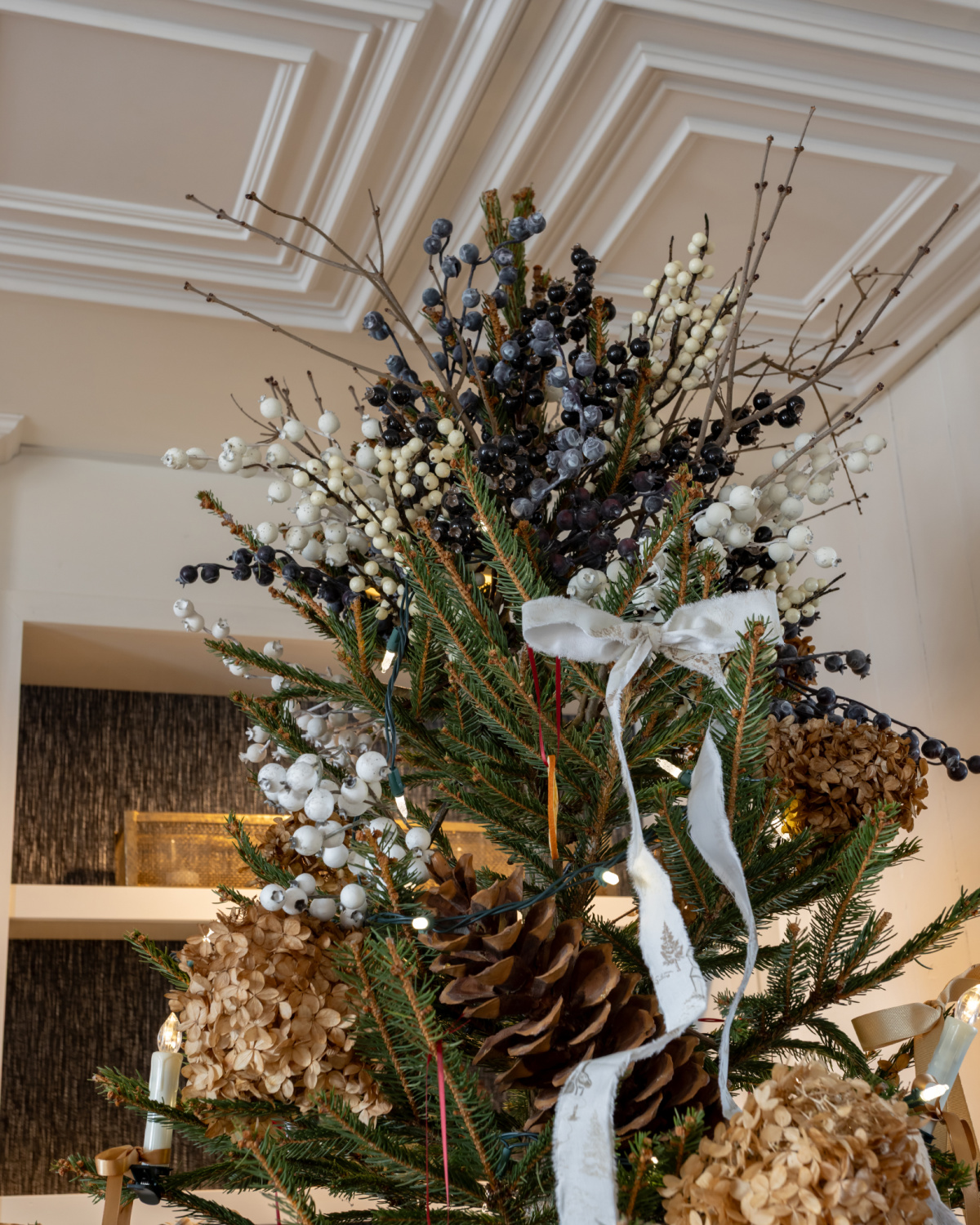 The finished berry tree topper with twigs, blue berries, and white berries.