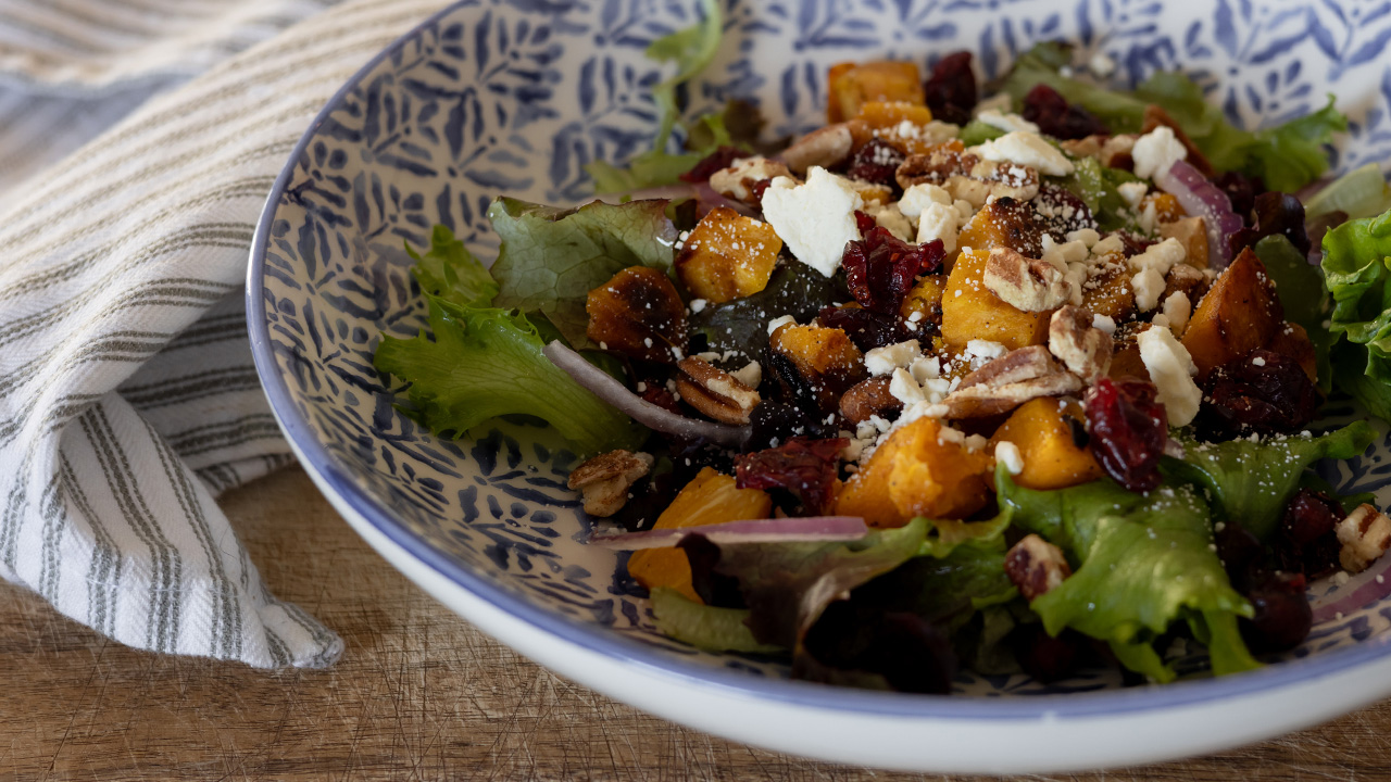 Roasted butternut squash salad in a blue and white bowl.