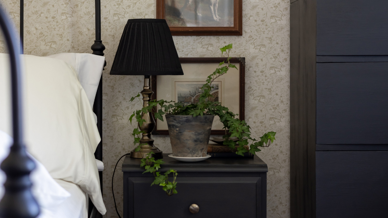 A lamp with a black pleated lampshade on a bedside table.