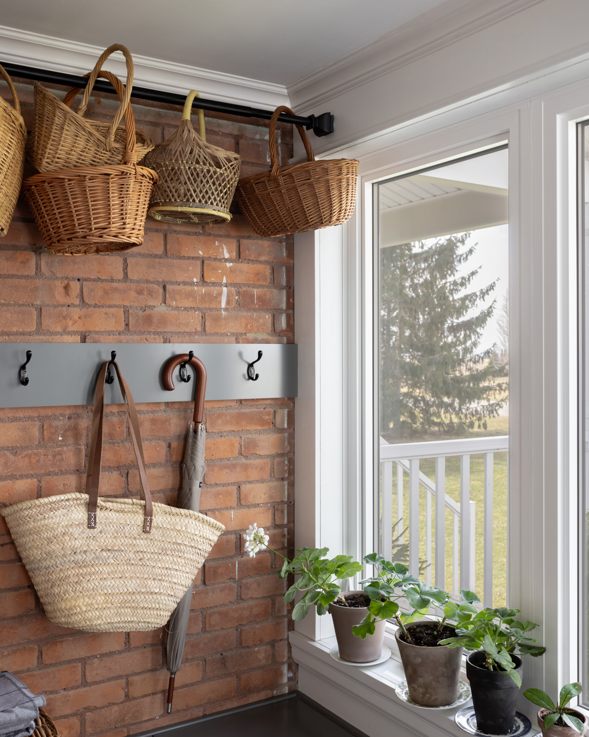 Handled baskets hung with a black tension rod in a boot room.