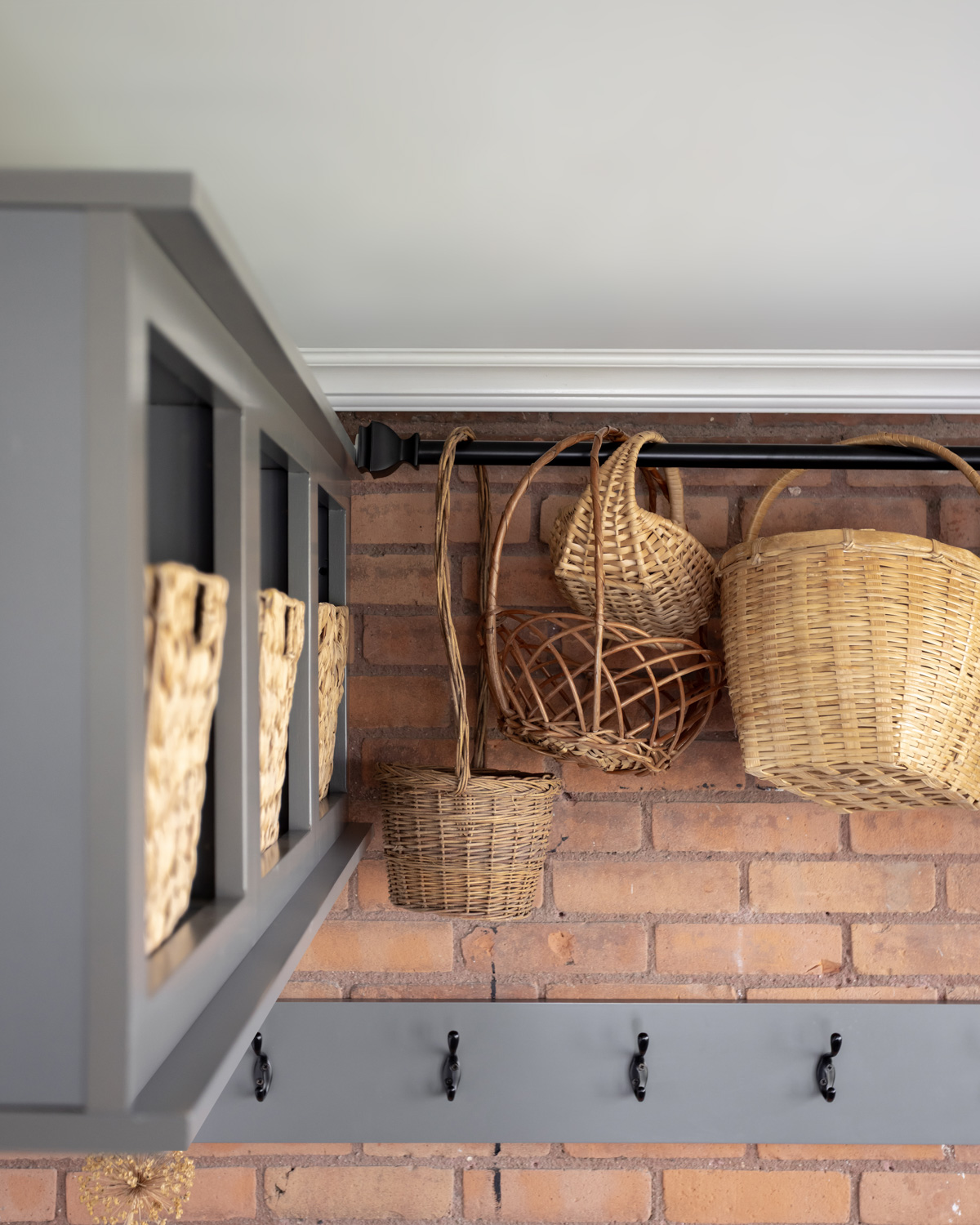 A variety of vintage baskets hanging from a tension rod.