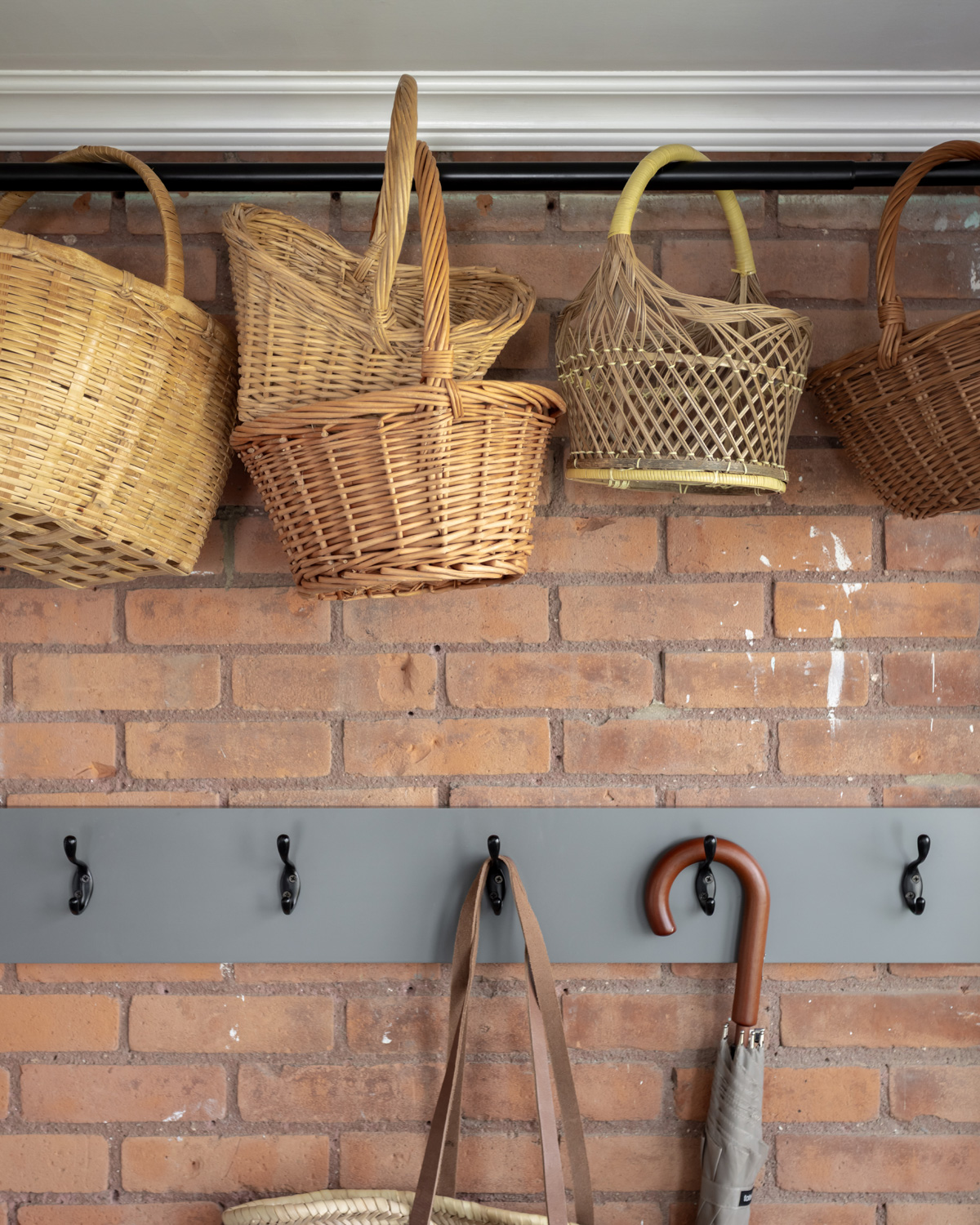 Baskets hanging in front of a brick wall.