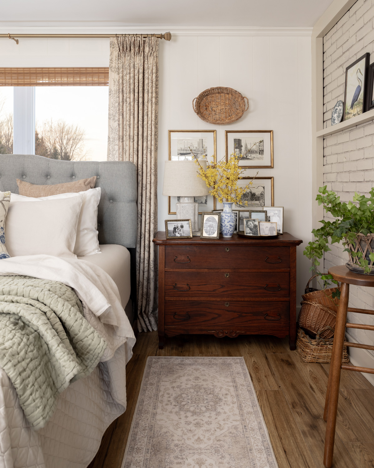 An antique dresser used as a bedside table in a bedroom.