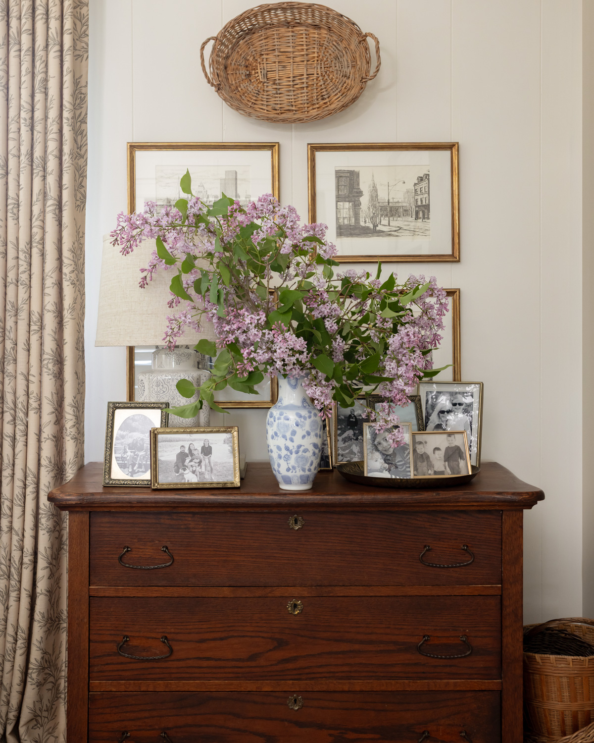 A vase of lilacs on an antique dresser.