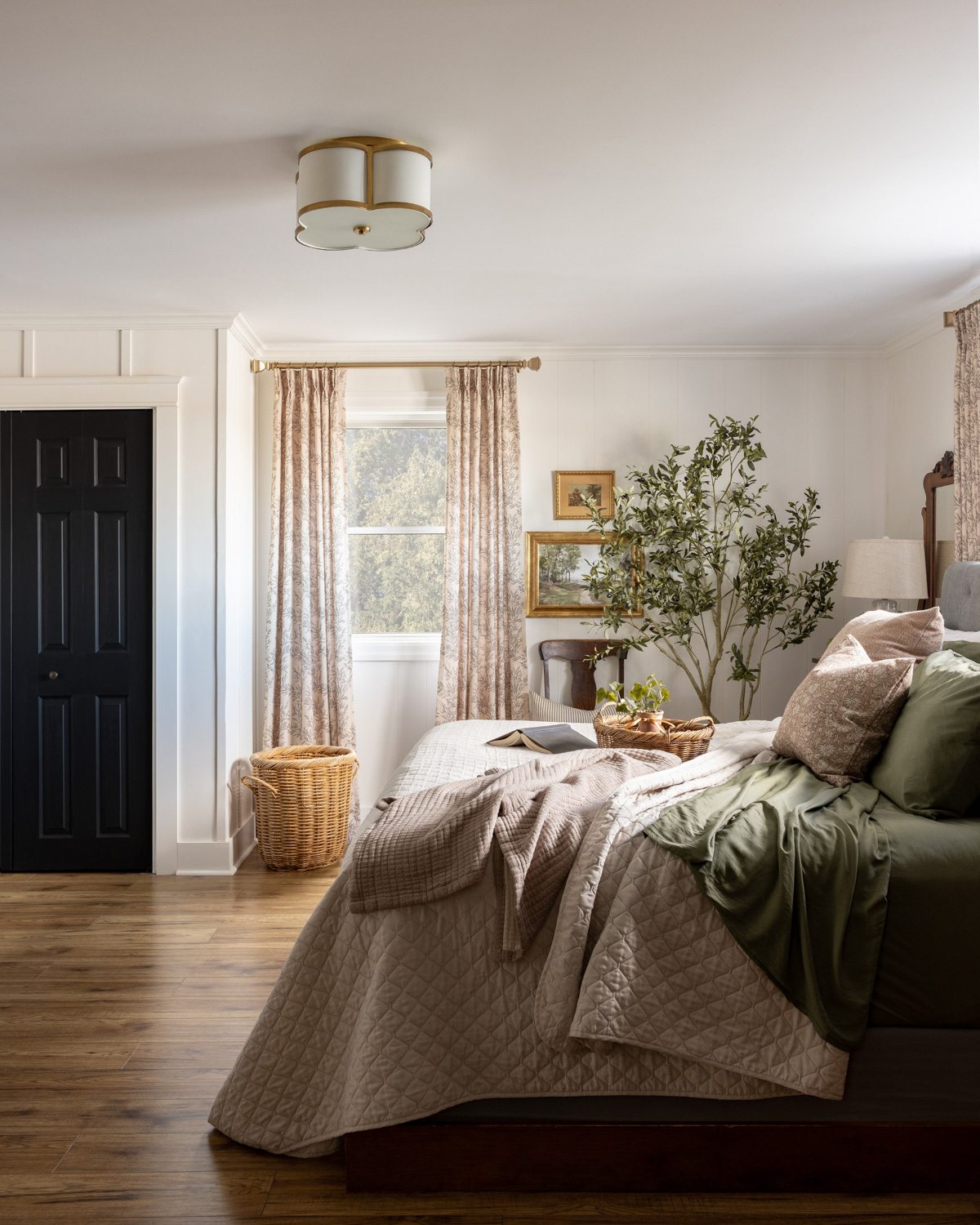A bedroom with patterned curtains and an olive tree.