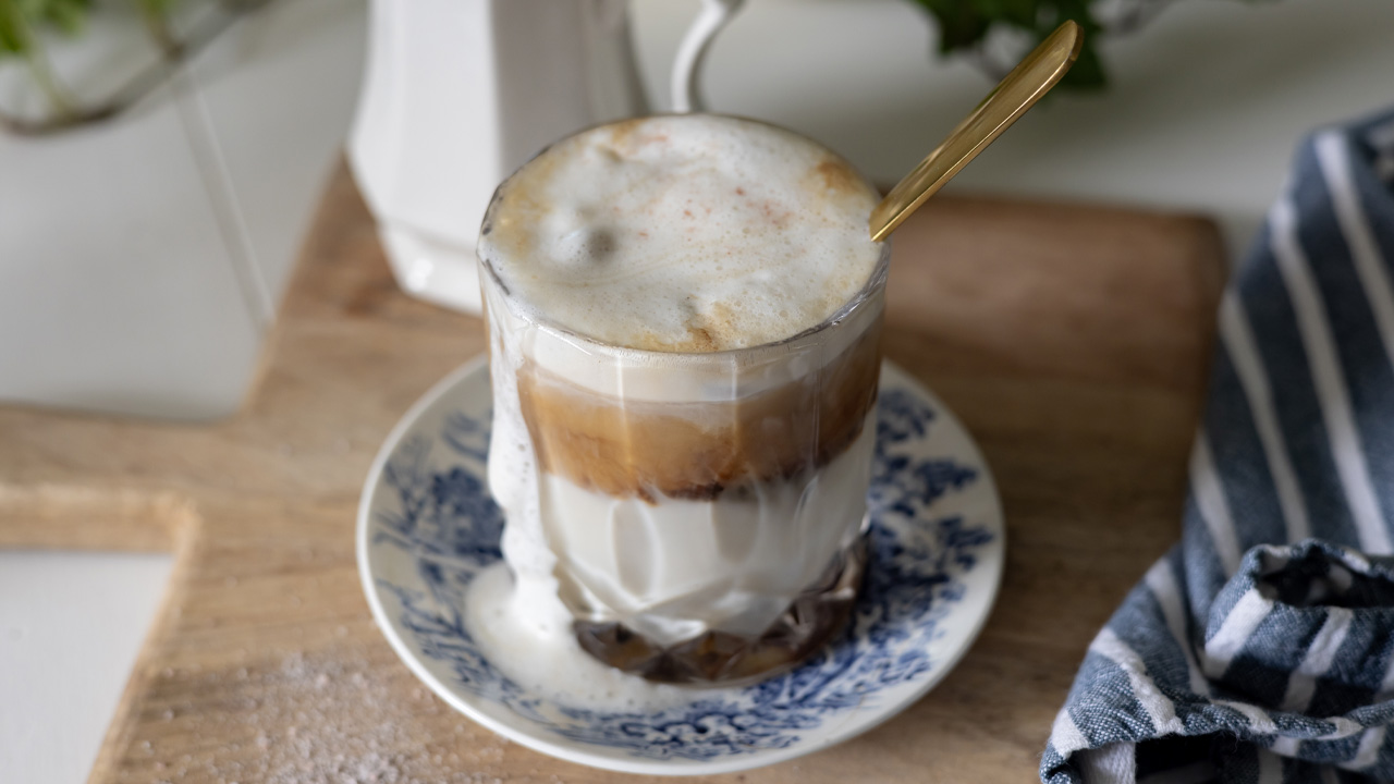 An iced latte with maple and Himalayan pink salt on a blue and white saucer.