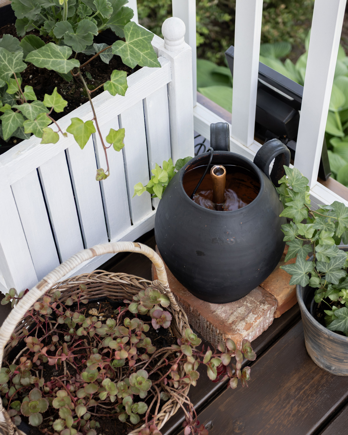 A solar powered fountain in a black vintage vase with a copper pipe.