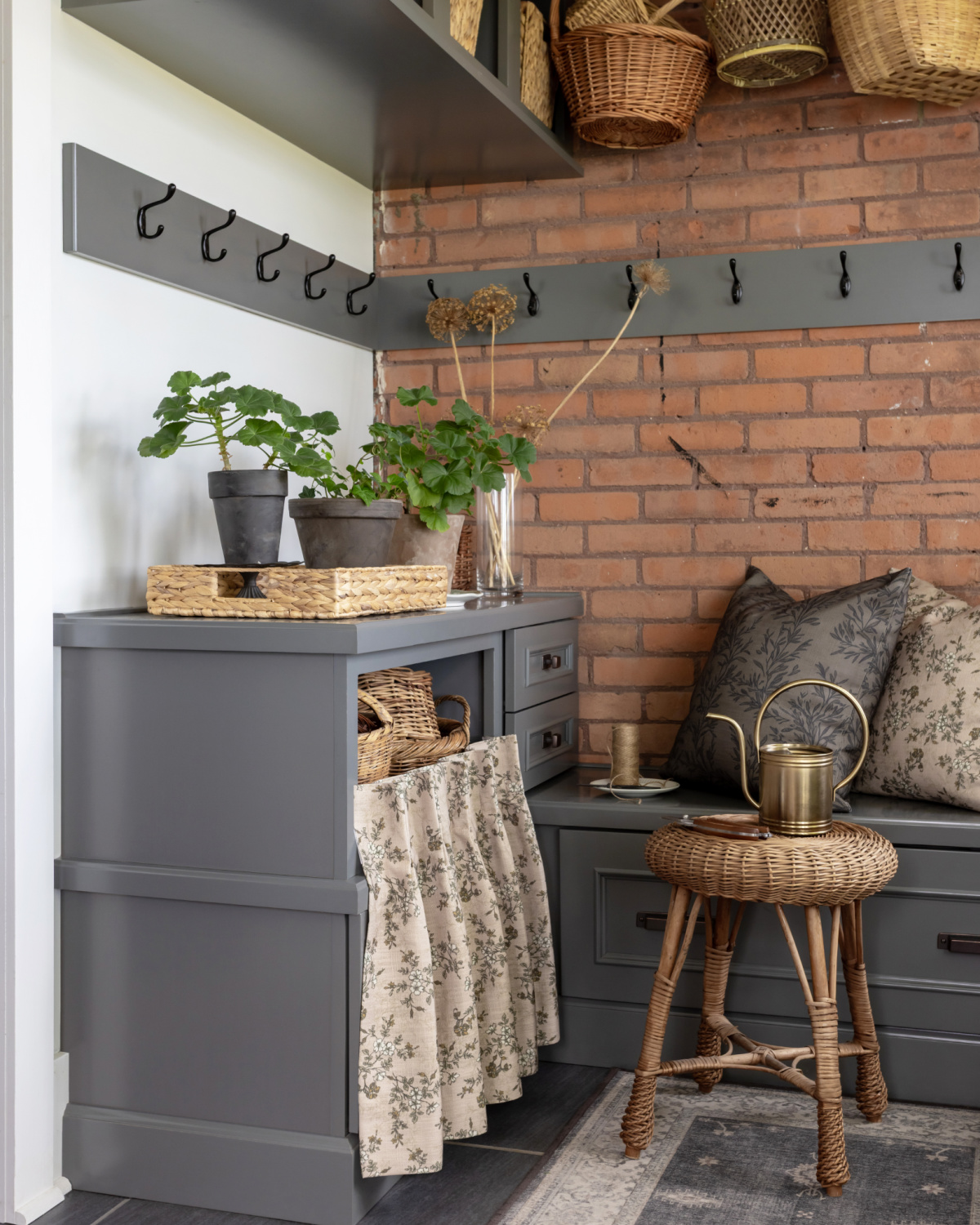 DIY skirted cabinet in a grey mudroom with exposed brick wall.