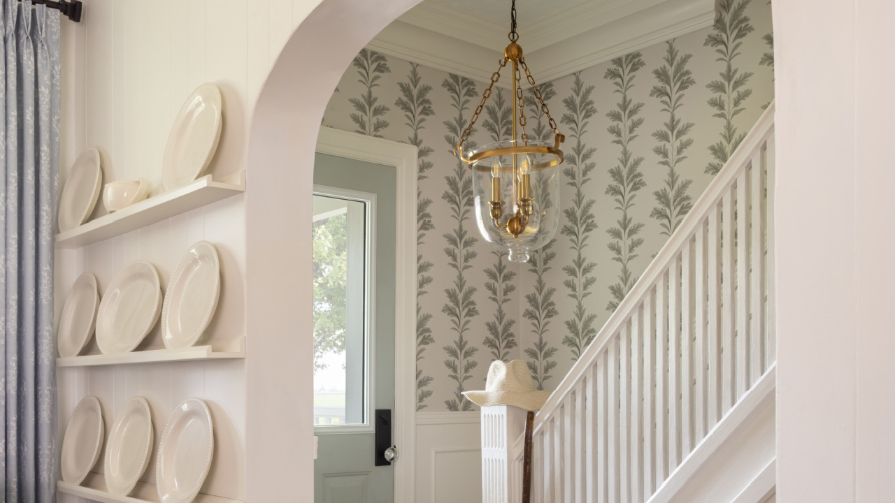 Restored front hall in a 120-year-old farmhouse with brass bell jar light and wallpaper.