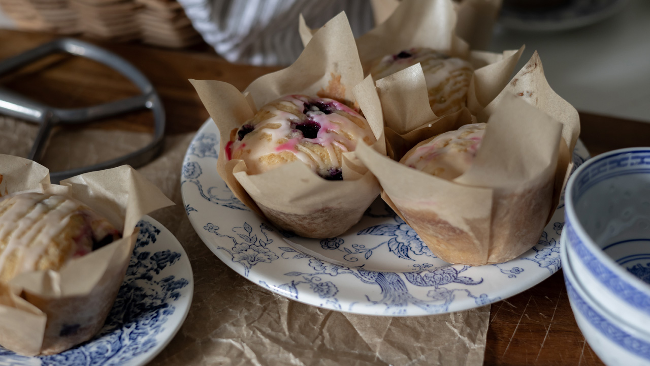 Classic lemon blueberry muffins on blue and white plates.