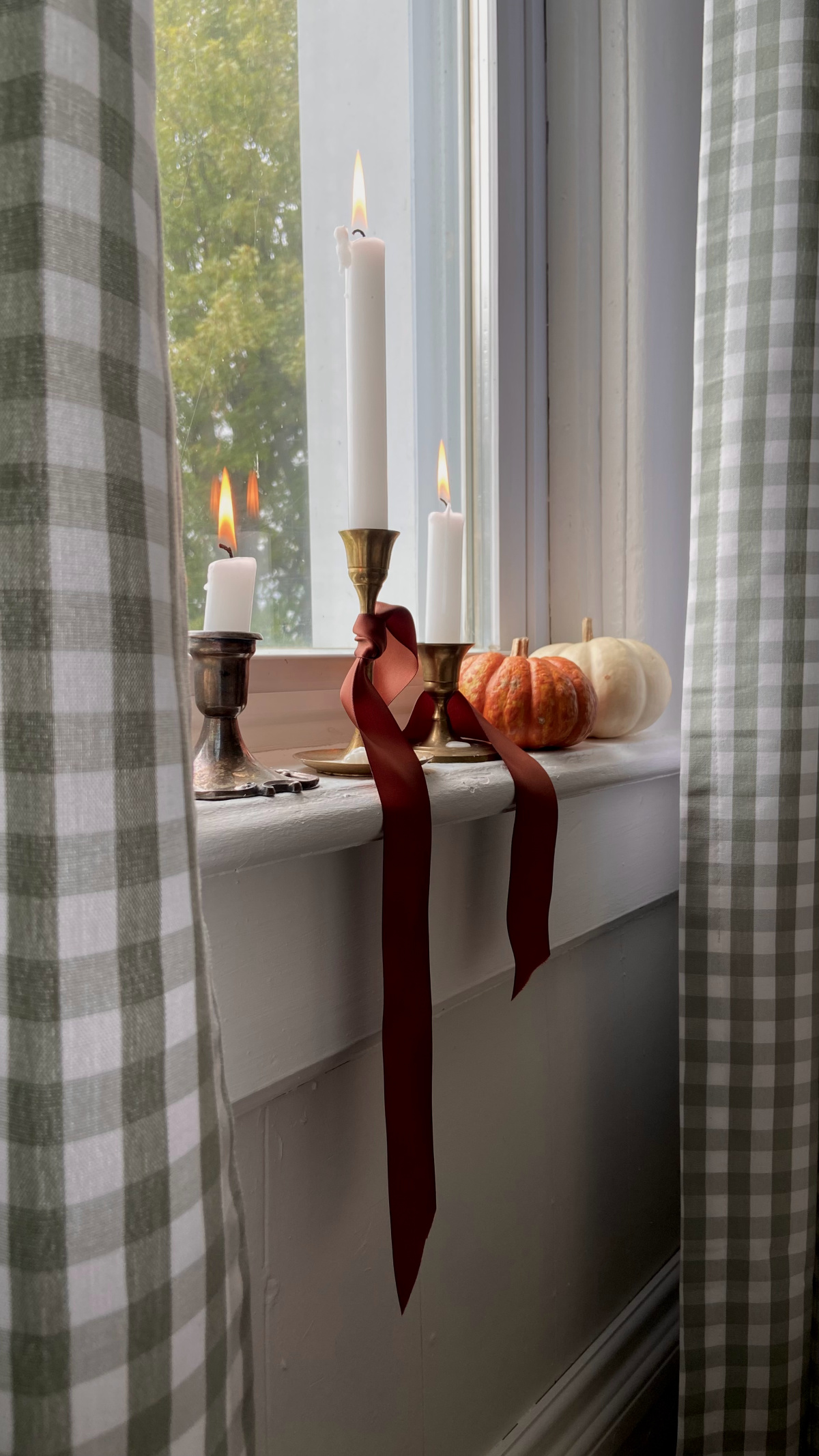 Candles on a windowsill with pumpkins