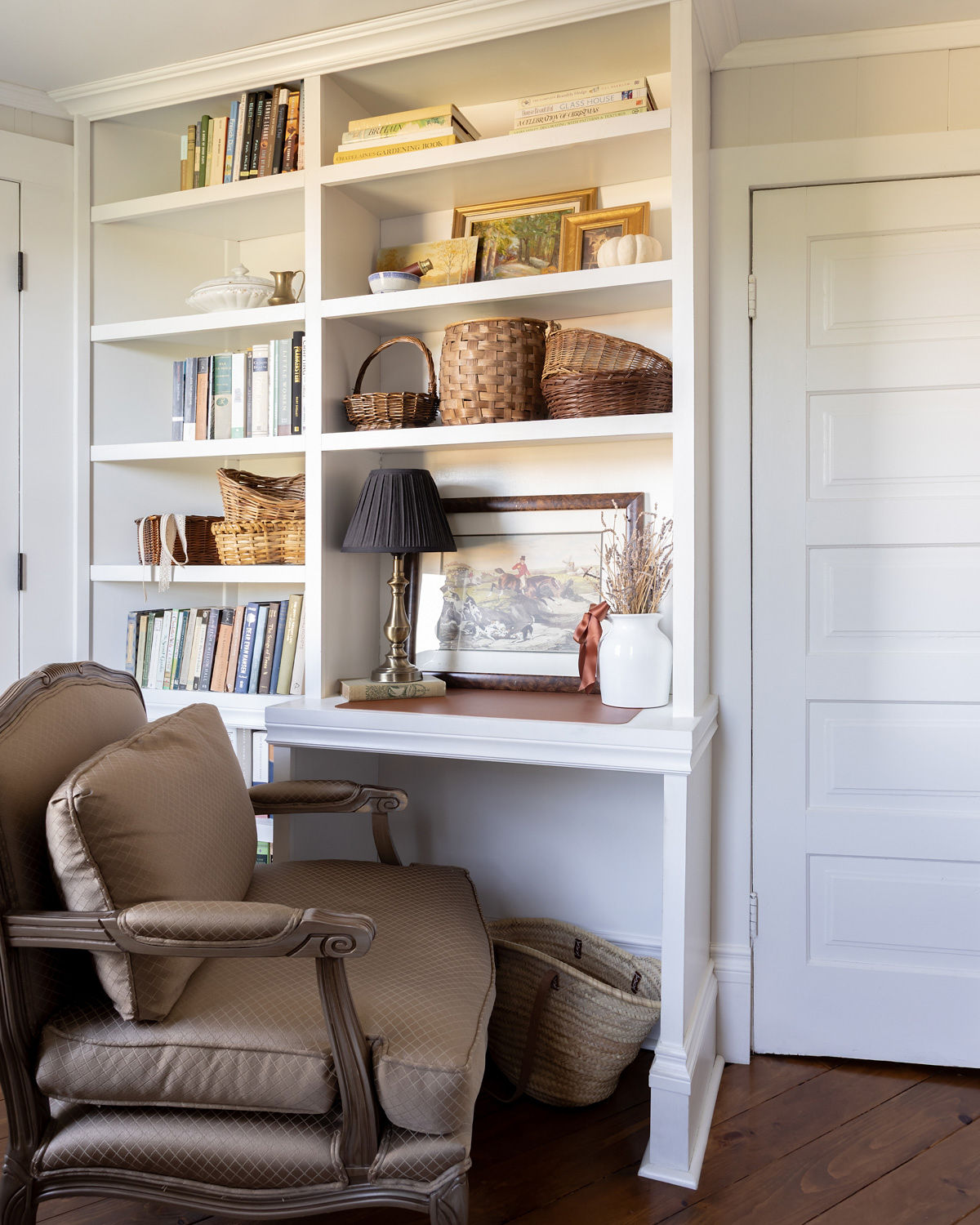 Built-in desk with bookshelves and a vintage bergere chair.