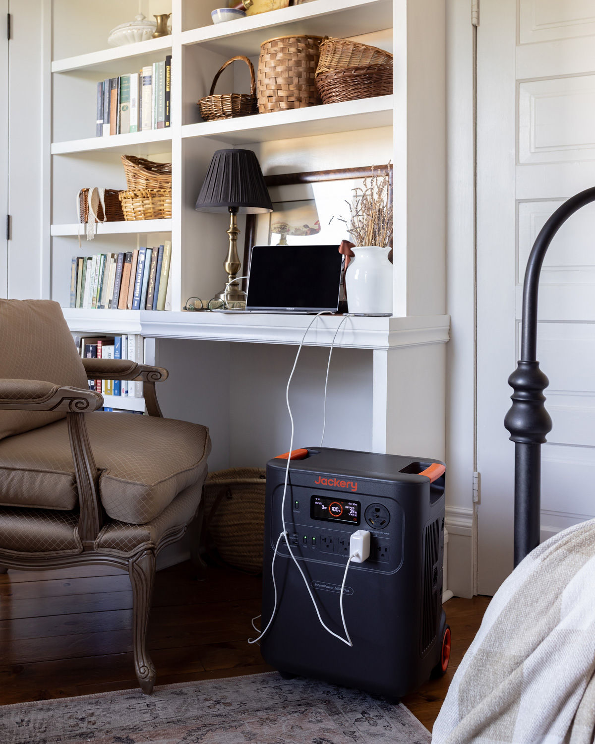 A Jackery HomePower 3600 Plus next to a desk with a laptop and phone plugged in.