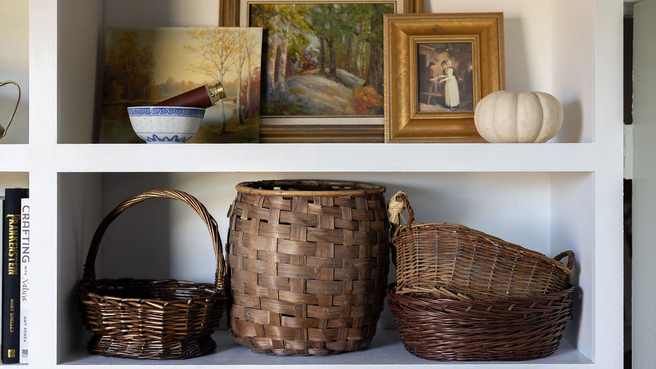 A built-in shelving unit styled with vintage baskets and oil paintings.